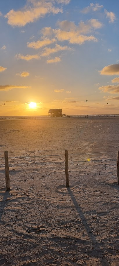 Zonsondergang achter een paalwoning op het strand