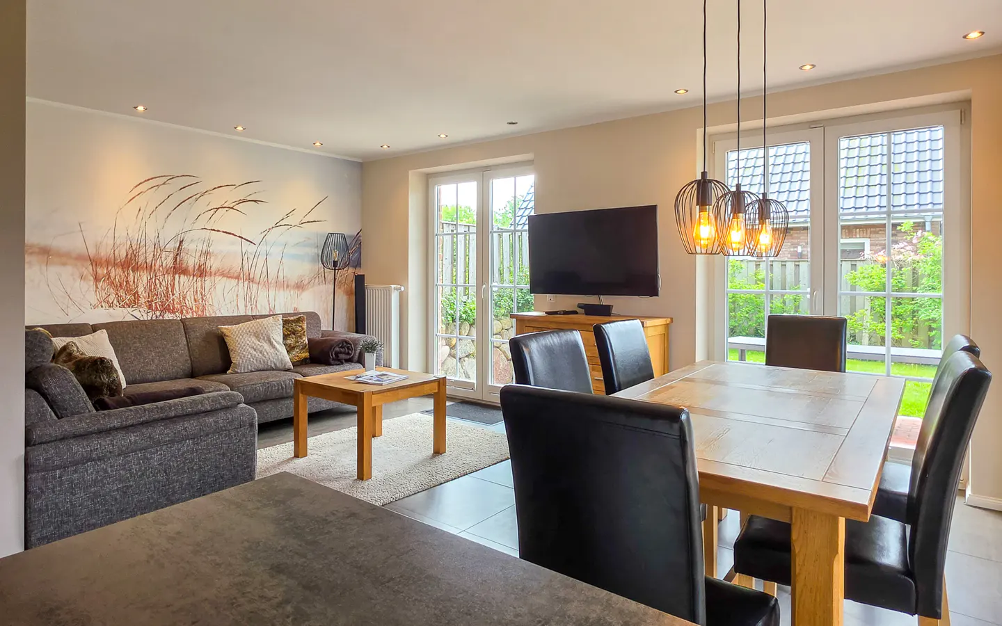 Åben stue og spiseplads med stor sofa og spisebord